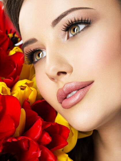 郁金香特写美女脸的年轻女子与鲜花迷人的模型与红黄色郁金香花束新鲜睫毛