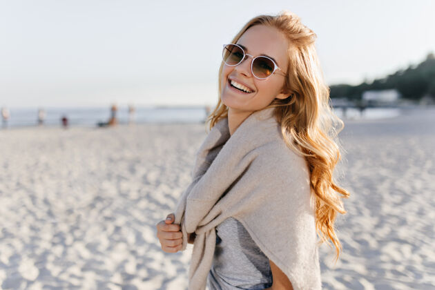 休闲一个戴着棕色太阳镜的漂亮女人在沙滩上笑海景金发休息