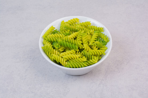 新鲜新鲜的绿色生螺旋通心粉放在白色盘子里食物好吃生的