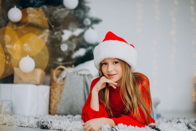 庆祝圣诞树下戴圣诞帽的漂亮女孩圣诞礼物圣诞老人