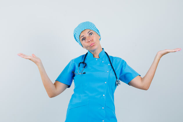 肖像身着蓝色制服的女医生表现出无助的姿态 神情迷茫 前视图年轻外科医生医院