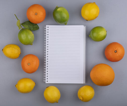 酸橙顶视图复制空间记事本与橙色柠檬和灰色背景上的酸橙空白复制柠檬色