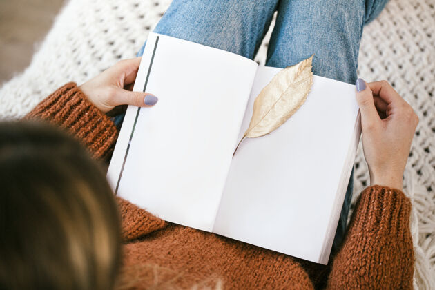 休闲坐在编织地毯上的女人 打开的笔记本上有一片金黄的叶子地毯阅读叶子
