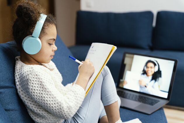 小侧视图的小女孩在网上学校与笔记本电脑和耳机女孩笔记本电脑学校