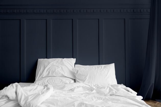 斯堪的纳维亚午夜蓝色卧室里床垫上的白色床单毯子舒适床