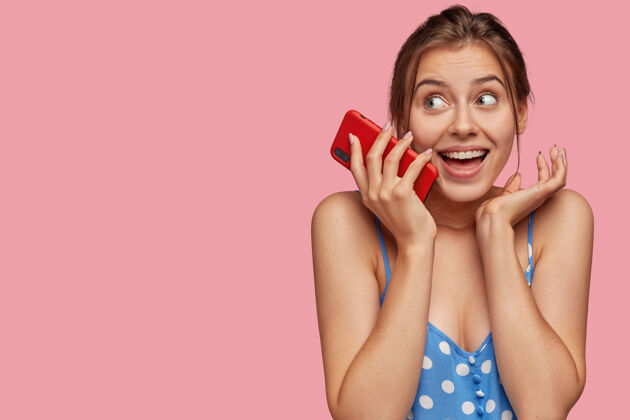 电子笑容可掬的年轻女性让现代红色智能手机近在咫尺快照信息自由空间