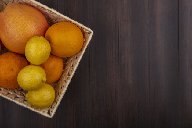 篮子顶视图复制空间橙子在一个篮子里与柠檬和葡萄柚在一个木制的背景视图五颜六色水果