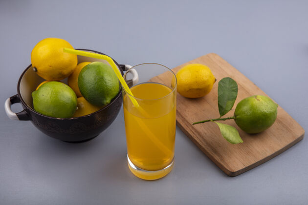新鲜侧视图柠檬与柠檬在一个平底锅与切菜板和橙汁在灰色的背景酸橙灰色水果