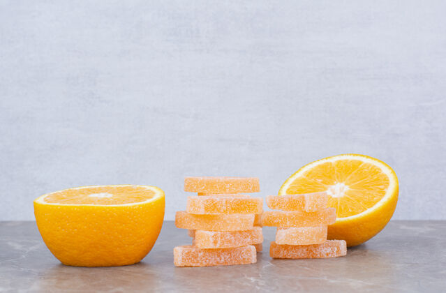 大理石新鲜的橘子片和甜甜的果酱放在大理石背景上果冻糖果水果
