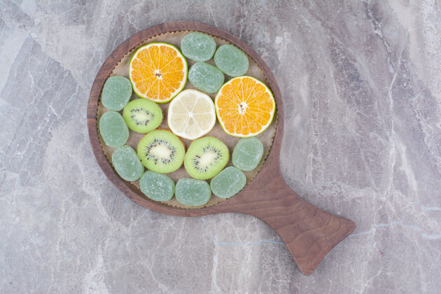 好吃在木板上放几片柑橘 猕猴桃和糖果木头柠檬水果