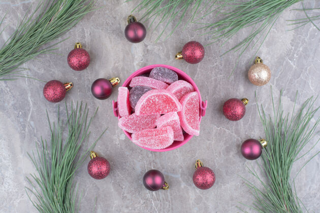 果酱一个粉红色的桶里装满了甜甜的果酱 大理石背景上有红色的圣诞球果冻糖果美味
