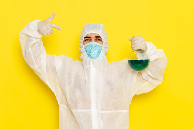 特殊正面图穿着特殊防护服的男科学工作者拿着浅黄色表面上有蓝色溶液的烧瓶封面工人服装