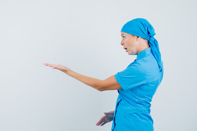 站立穿着蓝色制服的女医生伸着手做着困惑的手势医院实验室诊断