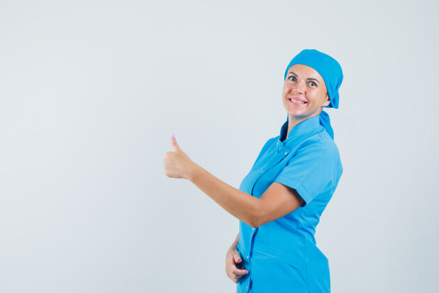 肖像身着蓝色制服的女医生向上竖起大拇指 看上去很高兴 正前方视图表演欢乐成人