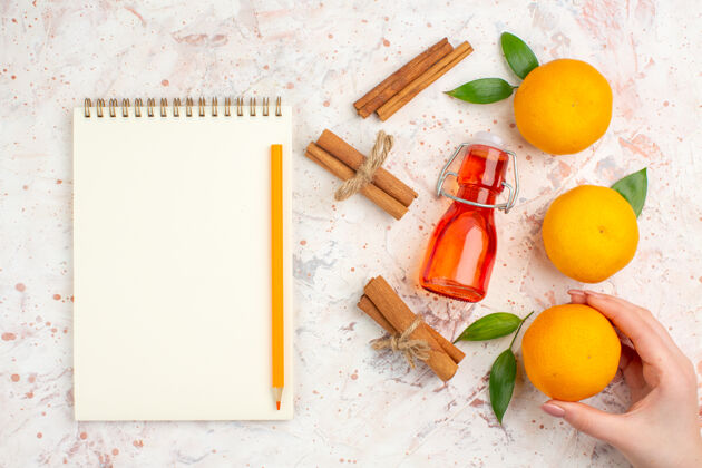 棒顶视图新鲜的橘子肉桂把橘子粘在女性的手瓶子里一支铅笔涂在明亮的表面上柑橘视图维生素