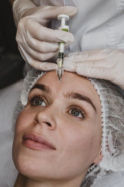 护理在健康中心接受面部美容注射的女人美容师过程美容