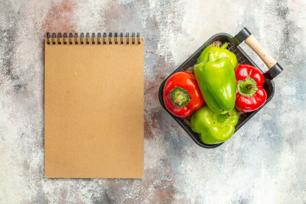观点顶视图绿色和红色辣椒在碗笔记本上裸体表面青椒和红椒蔬菜铃铛