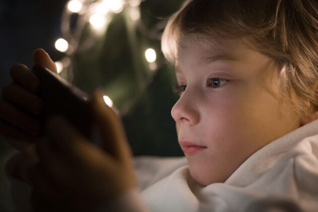 娱乐小男孩晚上在床上用智能手机水平科技移动