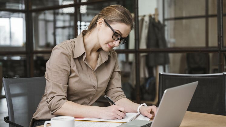 行政人员女商人在办公桌上使用笔记本电脑的侧视图工作女商人职业
