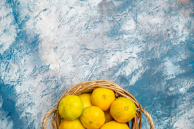 柠檬上半部分查看新鲜的柳条篮子在蓝白表面与复制空间的柑桔多汁顶部维生素