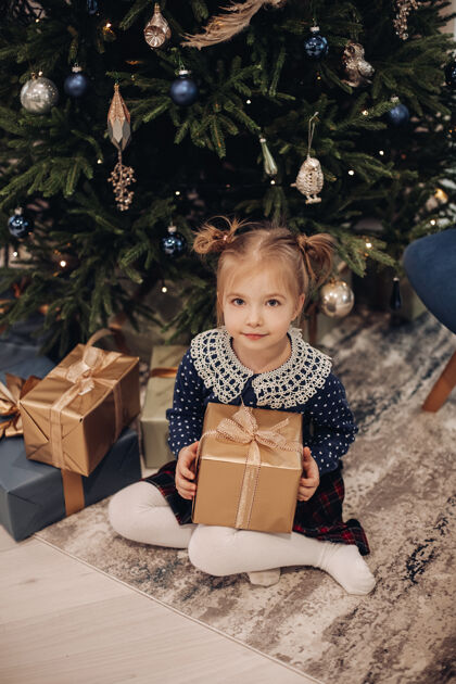 包装把腿放在下面拿礼物盒的女孩圣诞孩子礼物