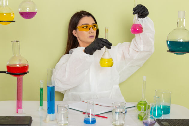 特殊前视图穿着特殊防护服的女化学家在绿色表面上处理溶液医学化学家化学