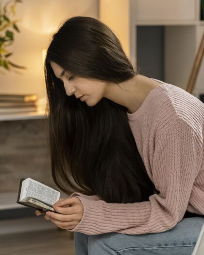 教义妇女一边读圣经一边祈祷的侧视图女人信条垂直