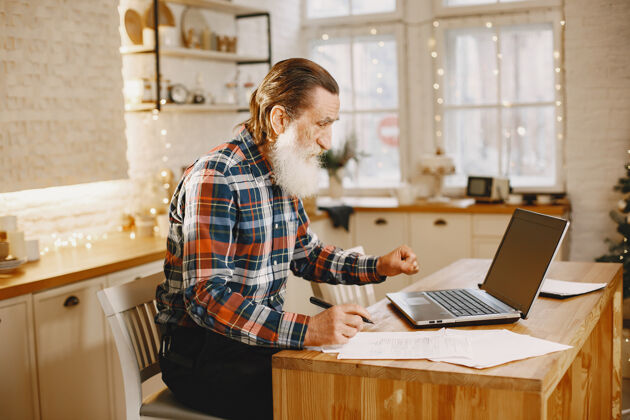内容拿着笔记本电脑的老人坐在圣诞装饰品里的爷爷穿手机衫的男人网站老年人通信