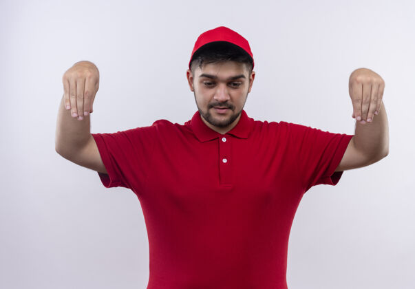 年轻年轻的送货员穿着红色制服 戴着帽子 自信地用手做手势 肢体语言概念信心红姿态