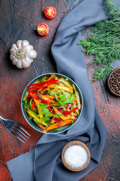 料理顶视图蔬菜沙拉在碗黑胡椒冷杉枝群青蓝色披肩大蒜盐在深红色的桌子上沙拉蔬菜冷杉