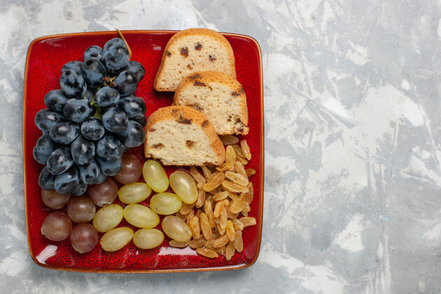 营养白色桌子上红色盘子里的葡萄和葡萄干蛋糕片俯瞰图水果饼干里面