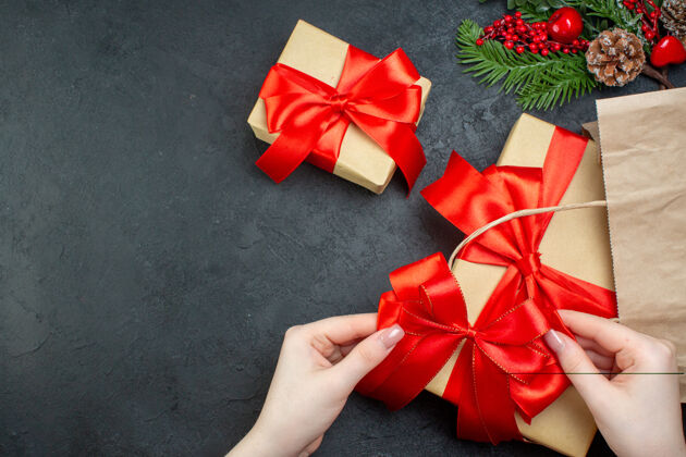 圣诞节上图：在黑暗的背景下 右侧有红色丝带的精美礼物 呈现圣诞气氛视图弓心情
