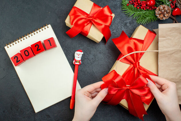 数字上图是圣诞节的气氛与美丽的礼物与红丝带和数字笔记本上的笔在黑暗的桌子上轮子风景钢笔