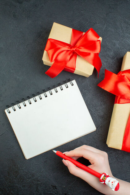 心情上图是圣诞气氛的美丽礼物和黑色背景上带笔的笔记本圣诞节风景信封