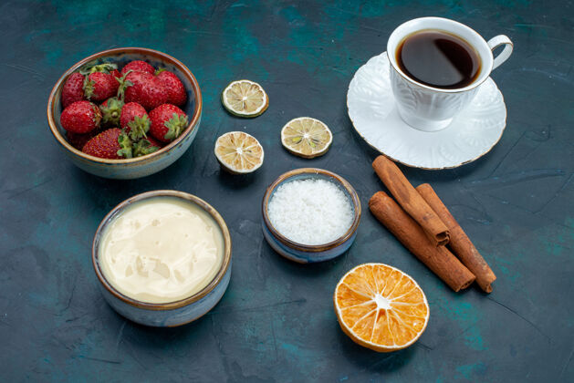 食品新鲜的红色草莓与肉桂和一杯茶在蓝色的桌子上的正面视图热的新鲜的前