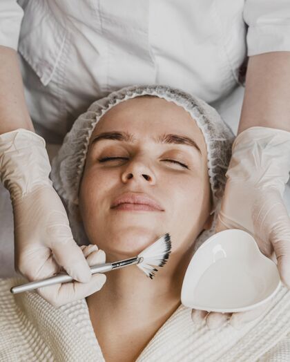 护理年轻美女面部皮肤护理俯视图美容师垂直水疗