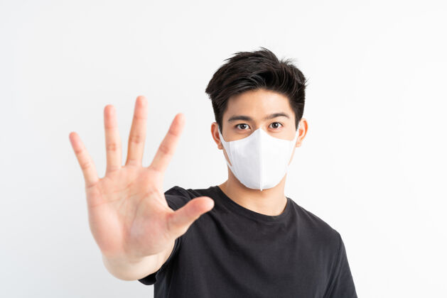 保健停止civid-19 亚洲男子戴口罩显示停止手势 停止电晕病毒爆发冠状病毒男性痛苦