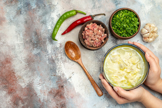 绿色俯瞰杜什巴拉饺子汤在一个碗里女人手大蒜辣椒木勺碗肉和绿色的裸体表面与复制空间肉胡椒大蒜