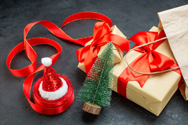 圣诞节侧视图美丽的礼物与红丝带和圣诞树圣诞老人帽子在一个黑暗的桌子上容器壁板圣诞老人