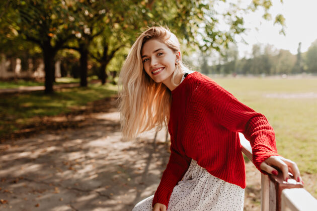 快乐微笑的金发女人在街上欢笑可爱的年轻女士在秋天的公园里感到快乐季节时尚游戏