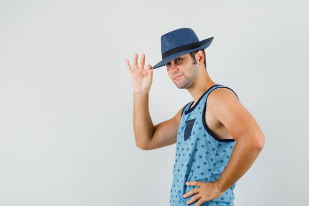 商人一个戴着蓝色单打帽的年轻人用手指抚摸着帽子 看上去很高兴现代男人交叉