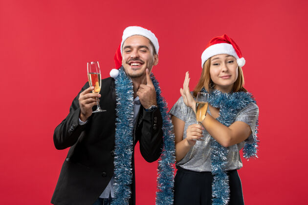 庆祝正面图年轻夫妇在红墙上庆祝新年爱圣诞色成人风景服装