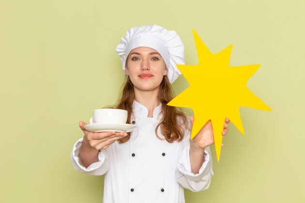 烹饪身穿白色厨师服的女厨师手持杯子 绿色墙上有黄色标志拿着饭菜护士
