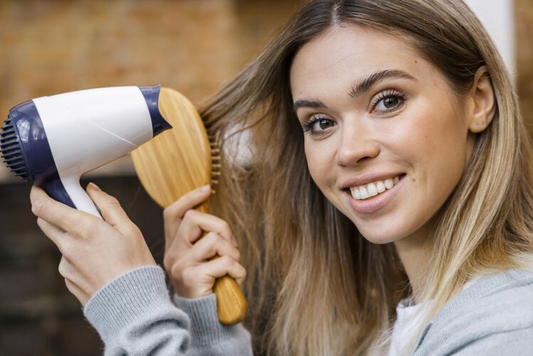 发型师女人用刷子吹干头发的侧视图美容院美发师美容师
