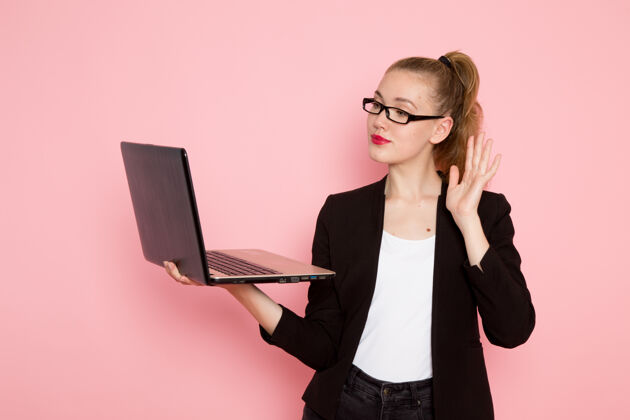笔记本电脑身穿黑色夹克的女上班族正对着粉色墙上的笔记本电脑抱办公室女商务员