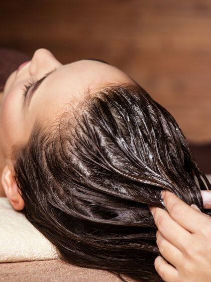 棕色头发美容师按摩女人头上的头发水疗美容水疗沙龙治疗身体健康