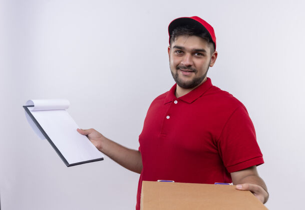制服年轻的送货员穿着红色制服 戴着帽子 拿着盒子和剪贴板 上面有空白页 要求签名空白问帽子