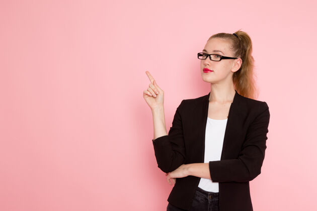 女商人身穿黑色夹克的女上班族在粉色墙上摆姿势的正面图前台女办公室