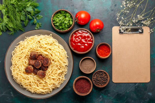 餐俯瞰煮熟的意大利面食 蓝色表面有肉丸和不同的调味品不同肉配料