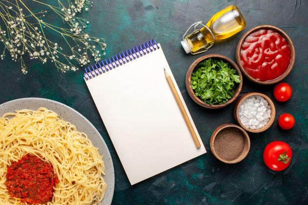 一餐顶视图煮熟的意大利面食与肉和不同的调味品在深蓝色的表面生的意大利菜烹饪